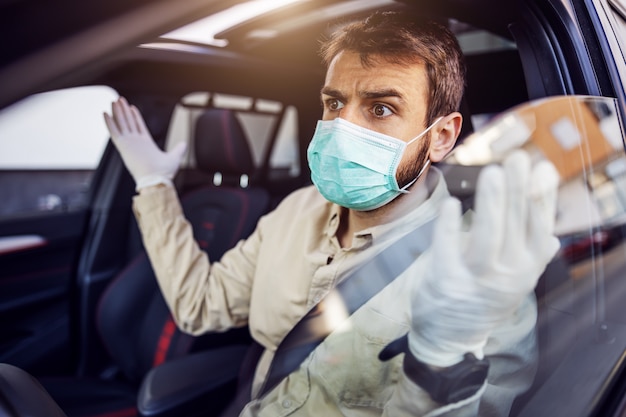 Man with e mask and gloves driving a car. Infection prevention and control of epidemic. World pandemic. Stay safe.