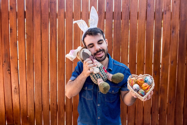 Человек с ухом пасхального кролика держит пасхального кролика и пасхальные яйца