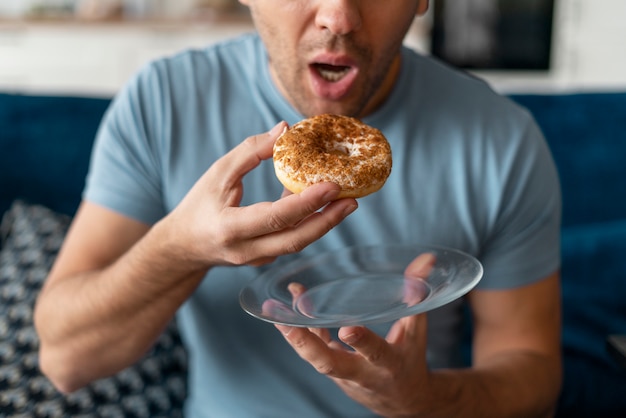 Foto uomo con disturbi alimentari che cerca di mangiare una ciambella