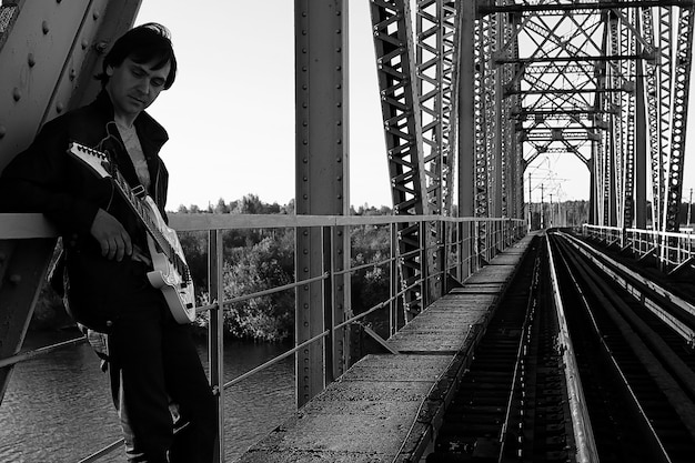 A man with an electric guitar in the industrial landscape outdoors monochrome