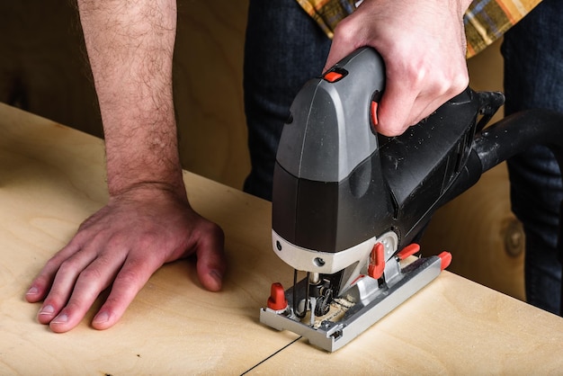 Man with electric jig saw cutting plywood