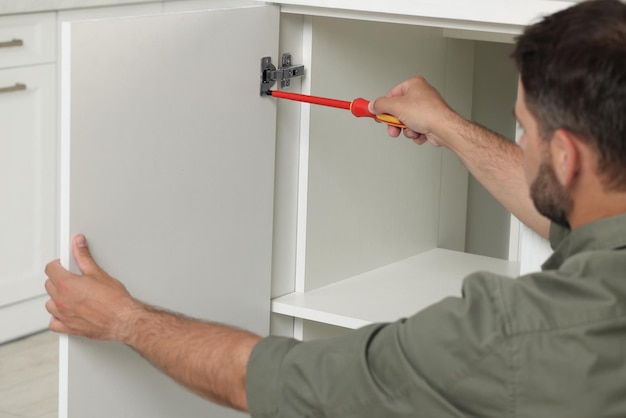 電動のスクリュードライバーを持った男性が室内で家具を組み立てている