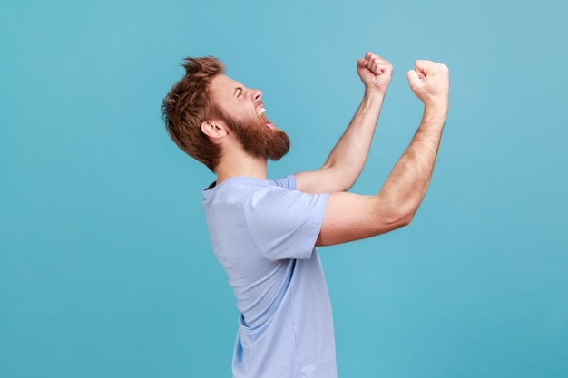 Man with excited expression raising fists screaming shouting yeah celebrating his victory success