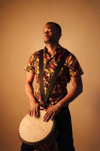 Photo man with eyes closed playing drum against brown background