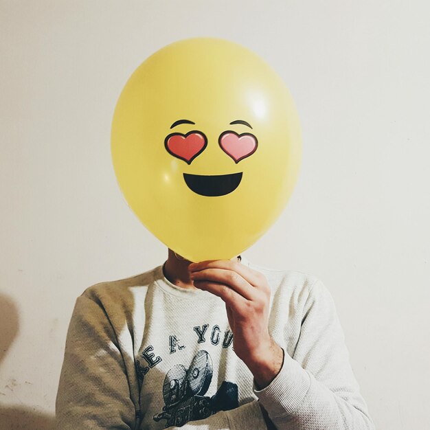 Photo man with face covered by balloon against wall