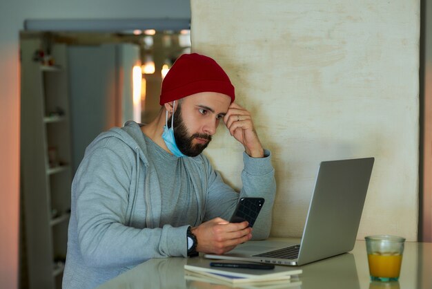 A man with a face mask working on his laptop