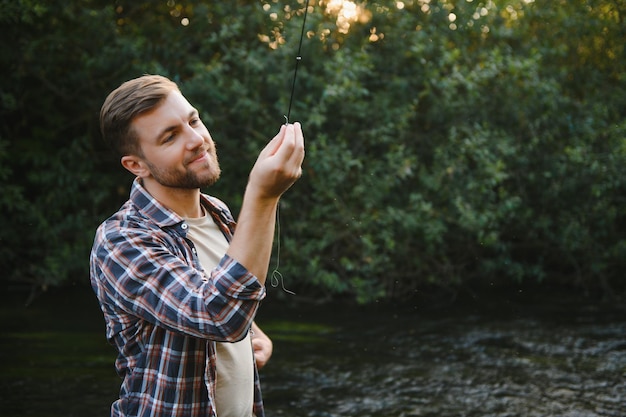 Man with fishing rod fisherman men in river water outdoor Catching trout fish in net Summer fishing hobby