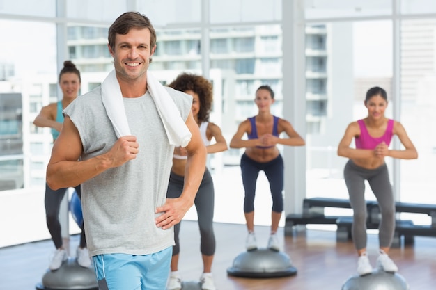 Man with fit people performing step aerobics exercise