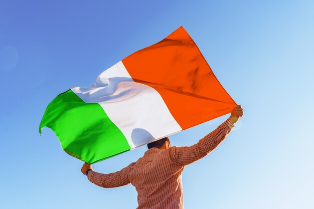 Man with a flag of Italy standing in morning field