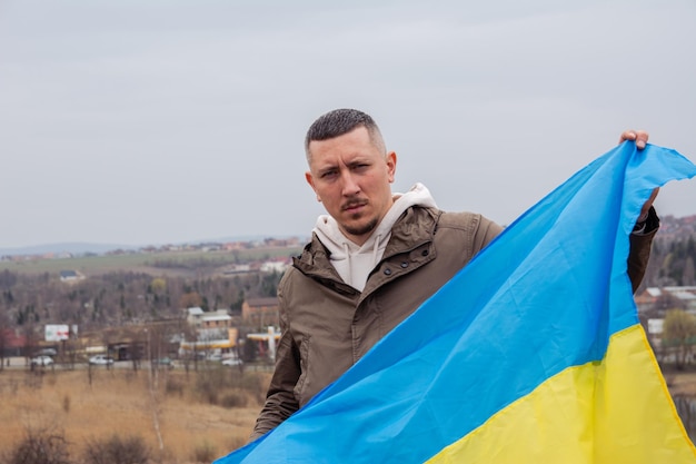 A man with a flag of Ukraine against the backdrop of a city and a lake in a Ukrainian cit