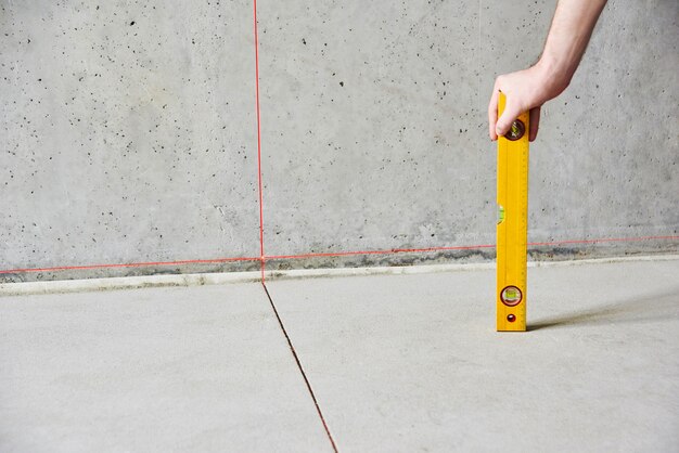 Man with floor level instrument check floor and walls