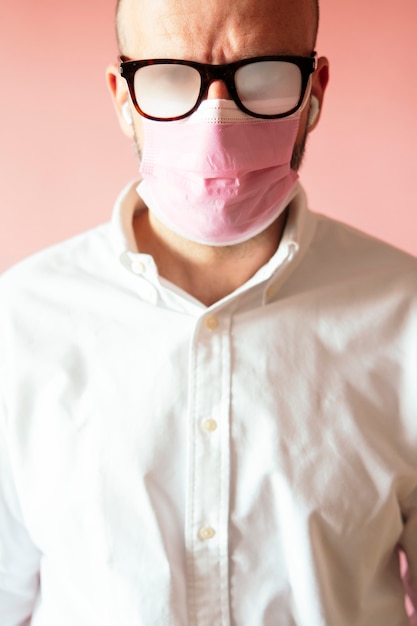 Photo man with foggy glasses because of the pink mask