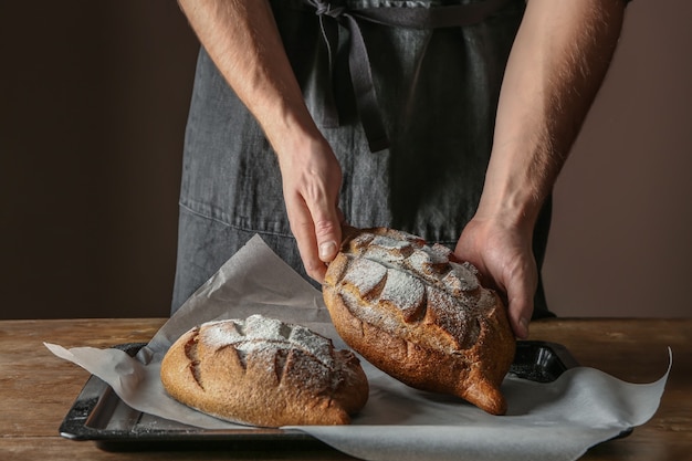 Man with freshly baked bread on table, closeup