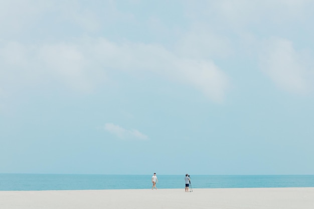Photo man with friend photographing at beach against sky