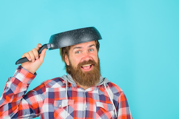 Man with frying pan on head crazy bearded chef happy man chef with pan saucepan cooking kitchenware