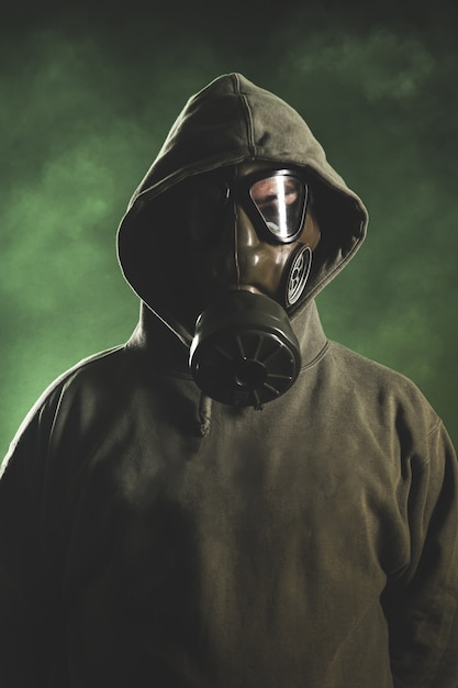 Man with gas mask on green background with smoke