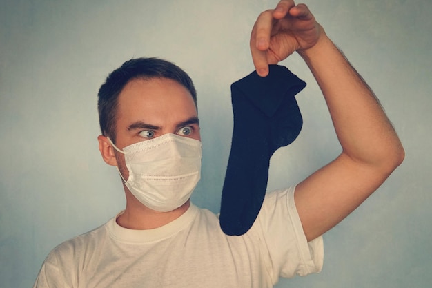 Man with gas mask is holding stinky sock unpleasant smell concept