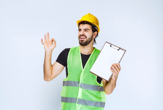 Man with gear holding the project folder and showing satisfaction sign.