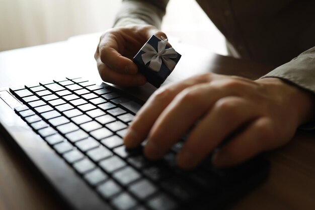 A man with a gift in his hand sits in front of the monitor\
screen order a gift for home and office