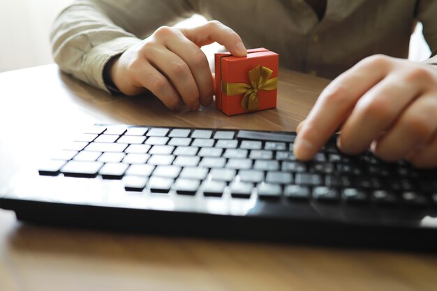 A man with a gift in his hand sits in front of the monitor\
screen order a gift for home and office