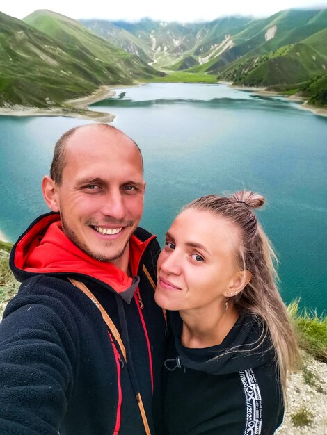 A man with a girl on the background of Lake Kezenoyam in the Caucasus mountains in Chechnya Russia June 2021