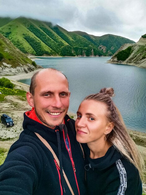 A man with a girl on the background of Lake Kezenoyam in the Caucasus mountains in Chechnya Russia June 2021