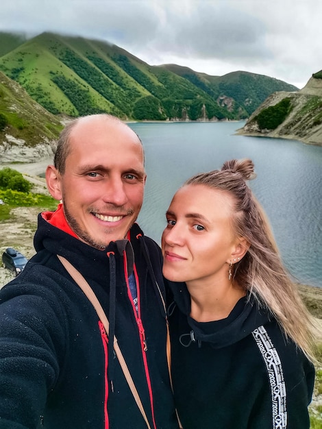 A man with a girl on the background of Lake Kezenoyam in the Caucasus mountains in Chechnya Russia June 2021