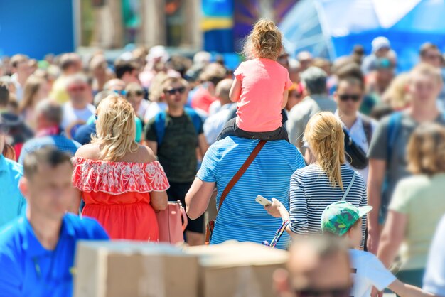 Man with girl in crowd of people walking on city street