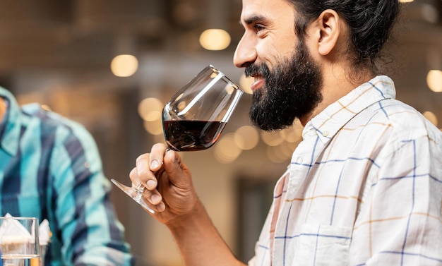 man with glass drinking red wine at restaurant