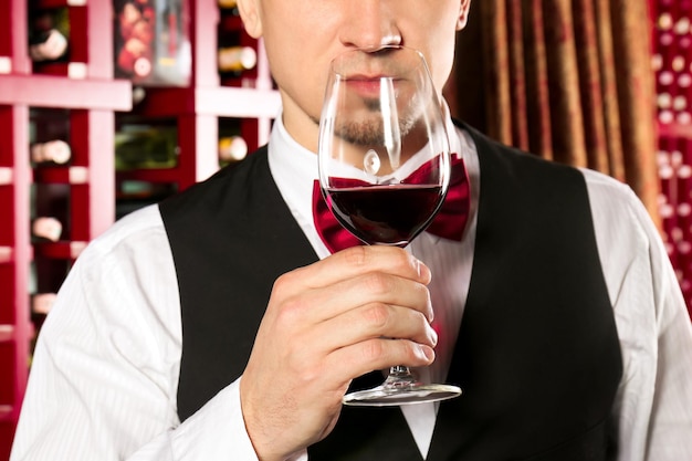 Man with glass of red wine in modern cellar