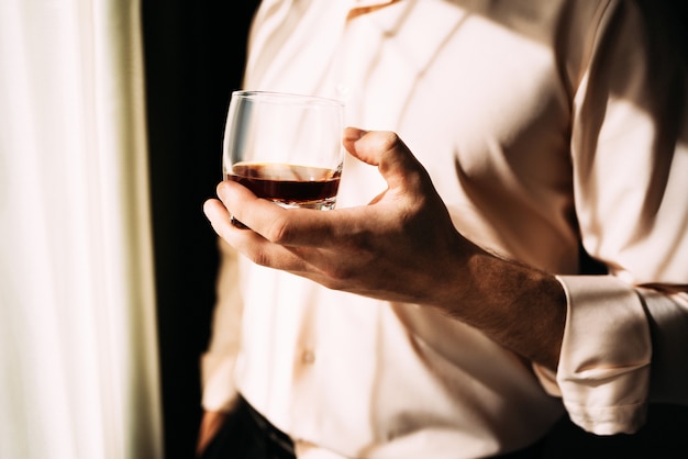 Мужчина с бокалом виски возле окна