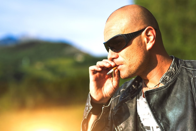 Man with glasses and black jacket smoking cigarette