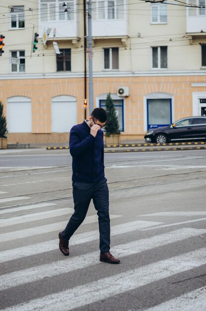 Un uomo con gli occhiali in mano attraversa la strada