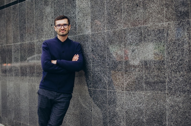 a man with glasses in his hand stands by the wall