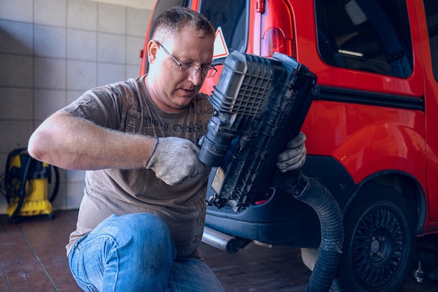 Photo a man with glasses maintains a car in a garage car repair by an experienced specialist in a car repair shop replacing the oil and filter in the car an auto mechanic performs car repairs