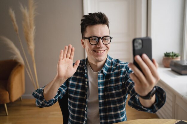 A man with glasses smiles during a video call looks into the camera with a welcoming
