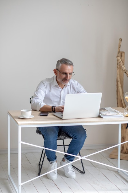 Man with glasses typing on laptop at table