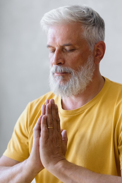 Man with gray hair meditates and does breathing exercises sports fitness and physical exercises for