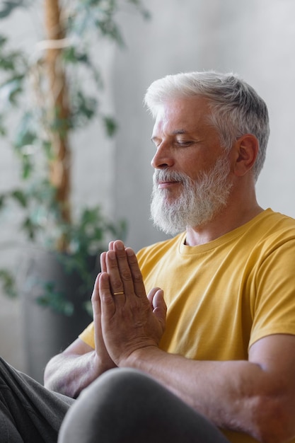 Man with gray hair meditates and does breathing exercises sports fitness and physical exercises for