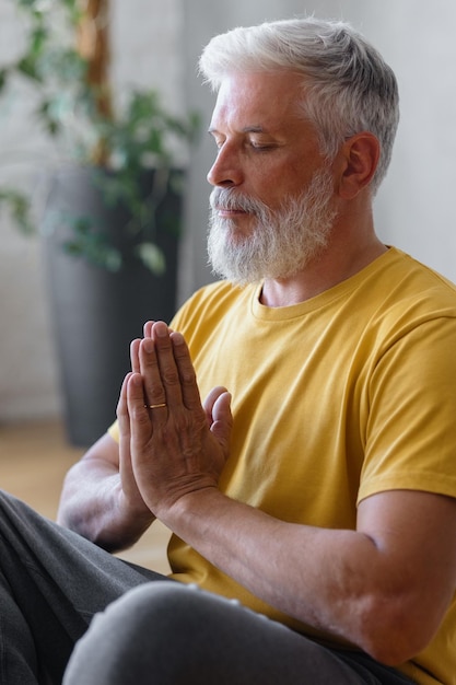 Man with gray hair meditates and does breathing exercises sports fitness and physical exercises for