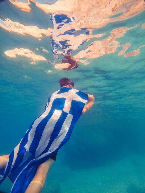 Man with greece flag swimming underwater sea vacation snorkeling