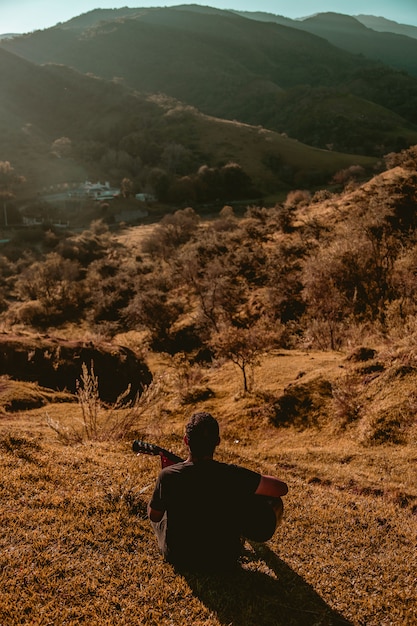 Man with guitar in mountains backlight