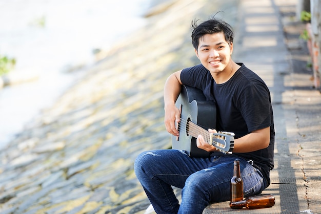 Man with guitar sitting outdoors