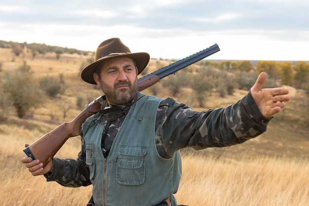 A man with a gun in his hands on a pheasant hunt in a wooded area in cloudy weather