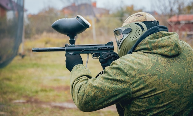 ペイントボールで遊ぶ銃を持つ男。屋外