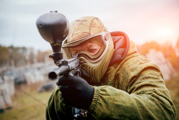 ペイントボールで遊ぶ銃を持つ男。屋外