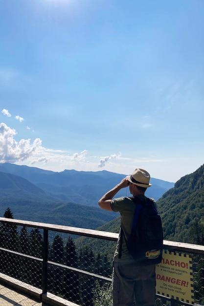 모자를 쓴 남자가 쌍안경으로 먼 곳을 바라보는 산 풍경 모바일 사진