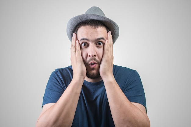 Man with hat surprised with hands on his face