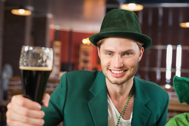 Uomo con un cappello che tosta una birra