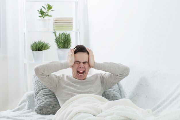 A man with a headache on the sofa